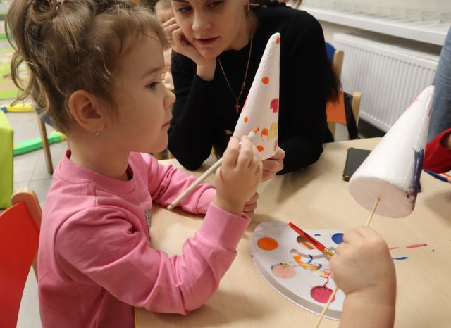 dziewczynka maluje farbkami styropianową bombkę