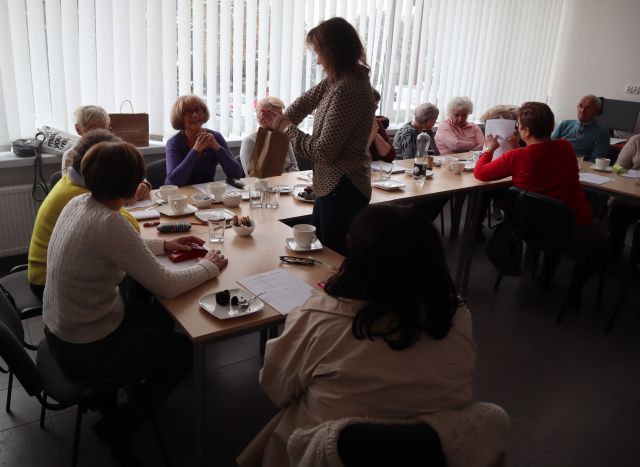 dyrektorka biblioteki częstuje seniorów czekoladkami