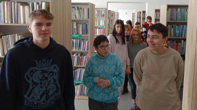 młodzież spaceruje pomiędzy regałami z książkami