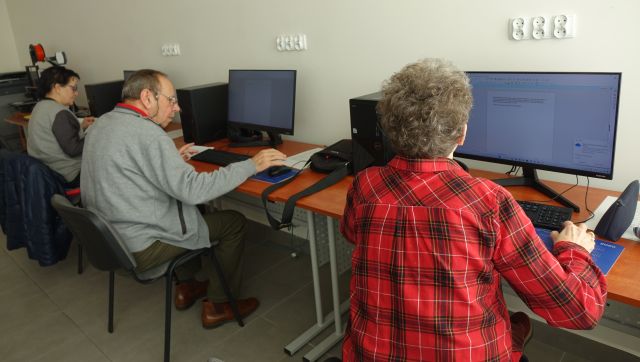 dwie seniorki i senior siedzą przed komputerami