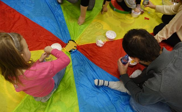 dzieci i rodzice wkładają małe białe kulki do butelek