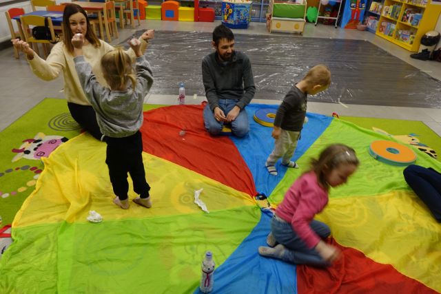 dzieci i rodzice na kolorowej chuście rzucała biały mi kulkami