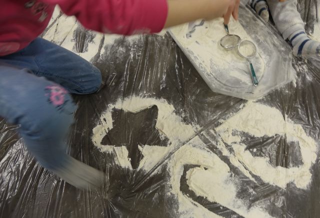 na szarej folii malarskiej wysypane z mąki symbole zimowe