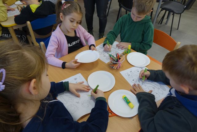 dzieci siedzące przy stolikach malują owoce i warzywa