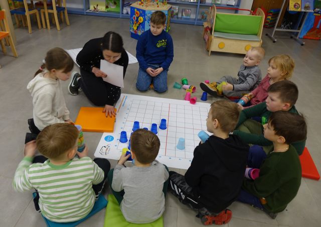 dzieci układają kolorowe plastikowe kubeczki na macie