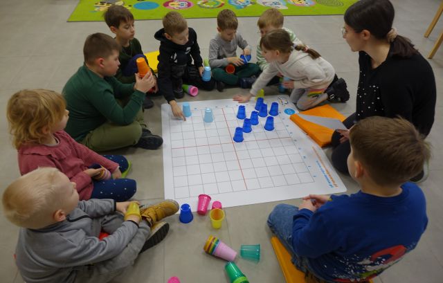 dzieci układają kolorowe plastikowe kubeczki na macie