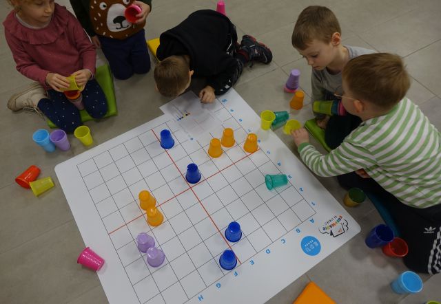 dzieci układają kolorowe plastikowe kubeczki na macie