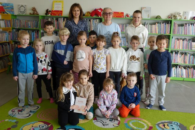 dzieci, bibliotekarki, kobieta i przedszkolanki pozują do zdjęcia w bibliotece