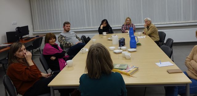 uczestnicy spotkania siedzą przy stołach