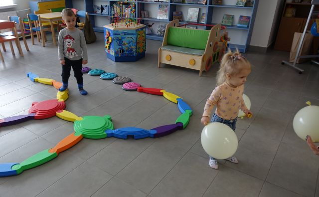 mała dziewczynka bawi się białym balonem i mały chłopiec spaceruje między ścieżką sensoryczną