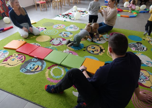 małe dzieci z rodzicami bawią się w kąciku malucha biblioteki
