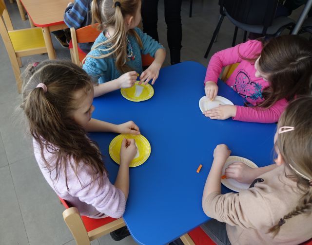 przedszkolaki kolorują na żółto papierowe talerzyki