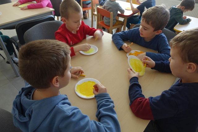 przedszkolaki kolorują na żółto papierowe talerzyki