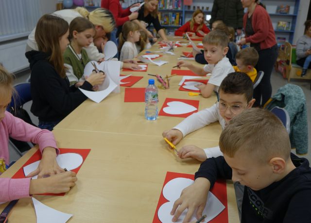 uczestnicy warsztatów odrysowują serca na czerwonych kartkach