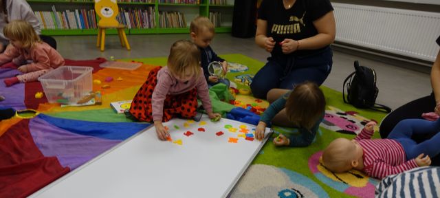 mała dziewczynka układa kolorowe literki na tablicy magnetycznej