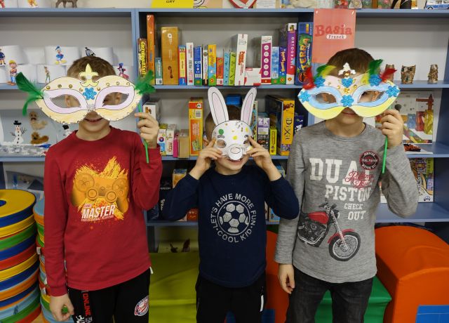 3 dzieci prezentuje wykonane przez siebie maski karnawałowe