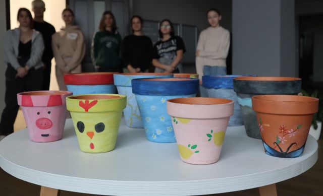 prezentacja pomalowanych przez młodzież doniczek, w tle stojąca młodzież