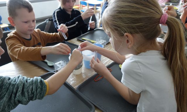 dzieci mieszają ciecz z farbkami, podając je pipetką