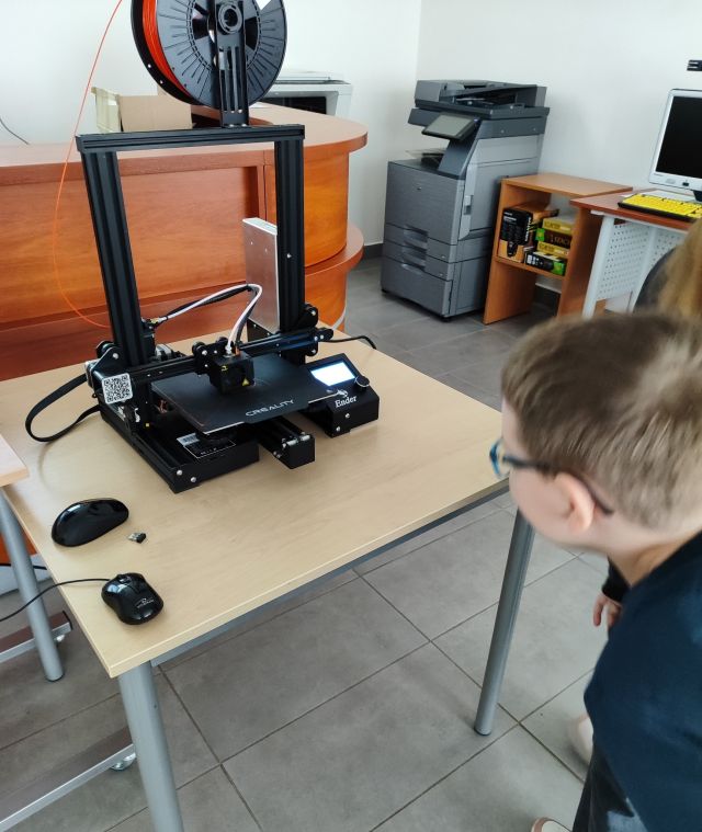 chłopiec patrzy jak drukarka 3d drukuje model samochodu