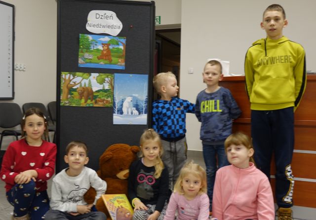 grupa 8 dzieci pozuje do zdjęcia na tle wystawki z okazjii Dnia NIedźwiedzia