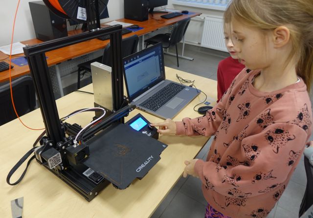 dziewczynka i chłopiec przyglądają się drukarce 3d
