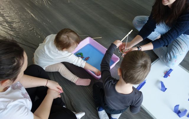 dwoje małych dzieci i mamy bawią się w wyławianie rybek
