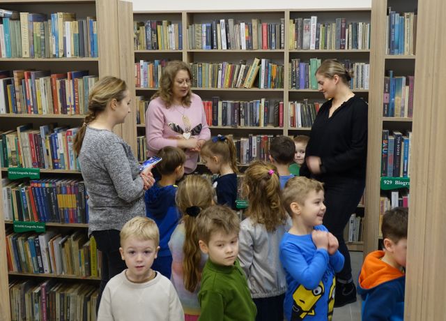 przedszkolaki pod okiem dwóch przedszkolanek i bibliotekarki zwiedzają pomieszczenia biblioteczne