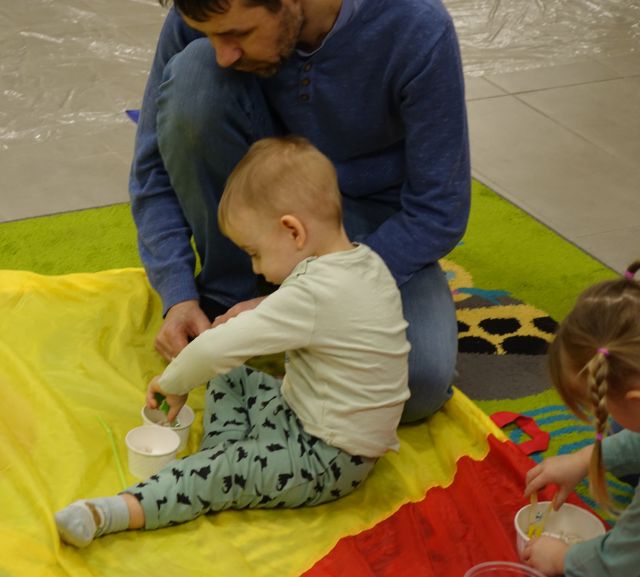 mały chłopczyk wyławia fasolki z kubeczka, obok siedzi mama