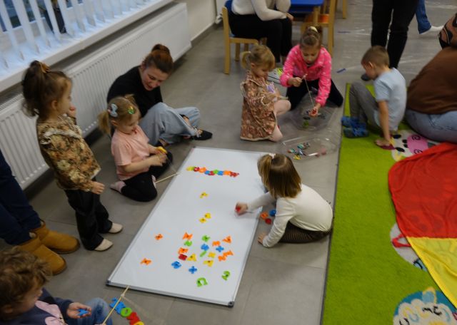 małe dzieci pod opieką rodziców układają literki