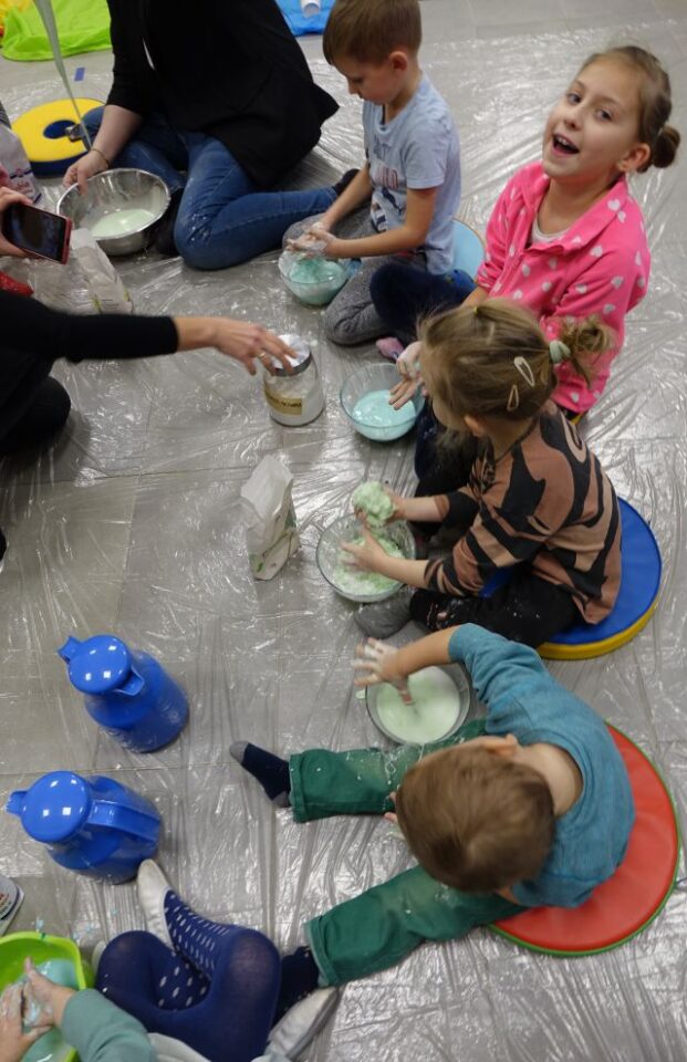 dzieci i rodzice dolewają wodę do mąki