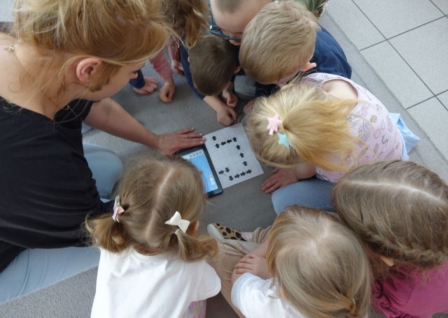 dzieci i nauczycielka sterują przy użyciu tabletów robotami Photon