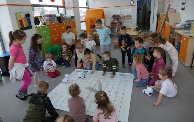 dzieci i nauczycielka sterują przy użyciu tabletów robotami Photon