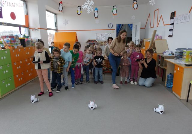 dzieci i nauczycielka sterują przy użyciu tabletów robotami Photon