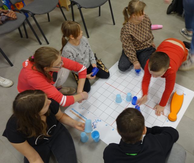 młodzież ukłąda kolorowe kubeczki na planszy