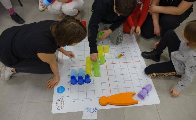 młodzież układa kolorowe kubeczki na planszy