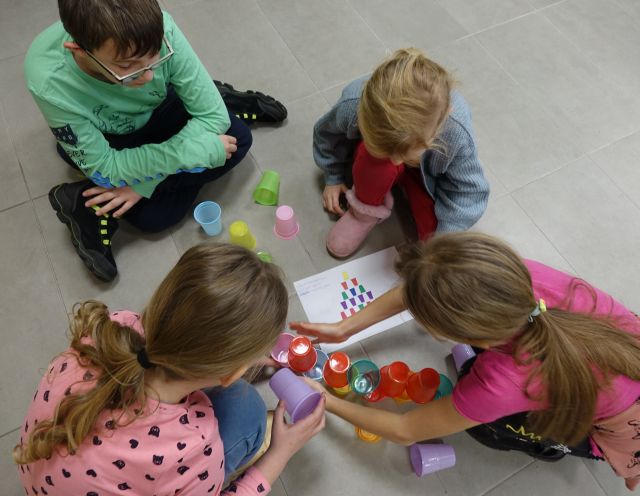 dzieci układają kolorowe kubeczki według wzoru z kartek