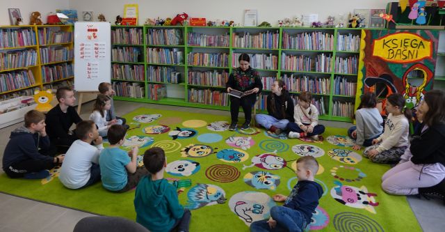 bibliotekarka pokazuje dziecim chińskiego smoka z papieru, w tle regały z książkami