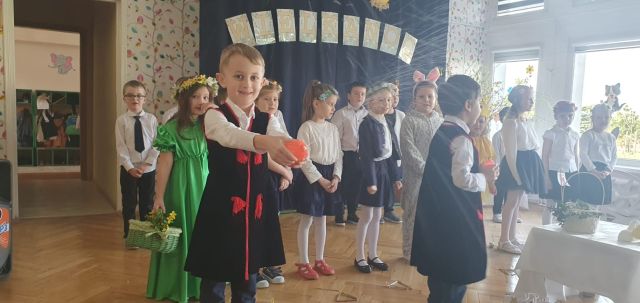 chłopiec psikawką leje wodą gości, za nim w tle stoją przedszkolaki