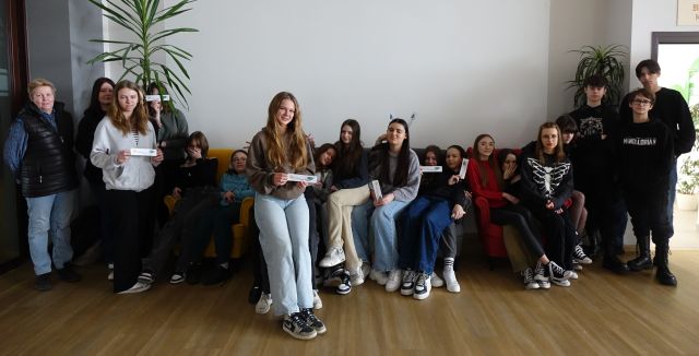 młodzież pozuje do zdjęcia siedząc na sofie i kolanach kolegów