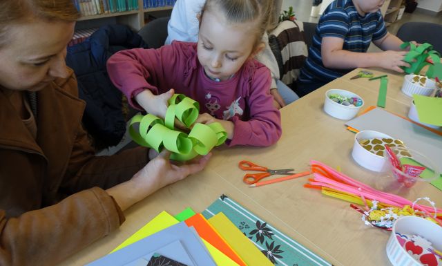 dziewczynka robi kwiatka z zielonej kartki