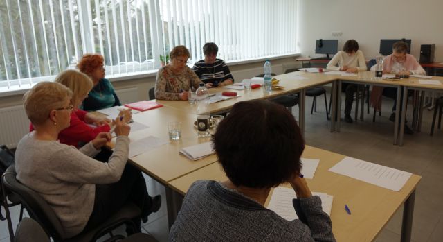 seniorki siedzą przy stołach i notują na kartkach