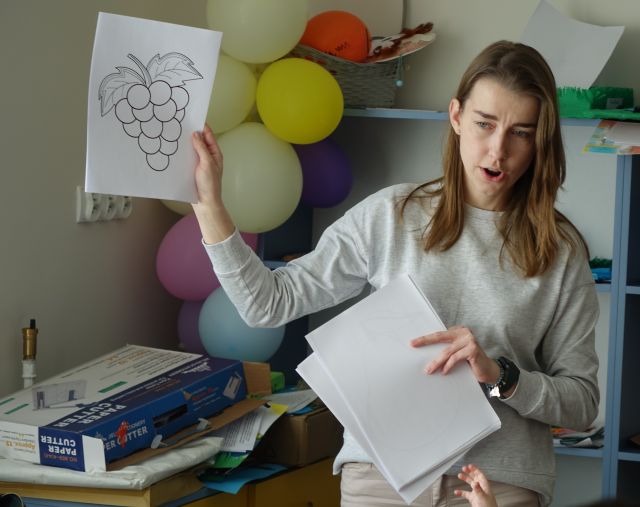 kobieta pokazuje kartkę z zarysem winogrona