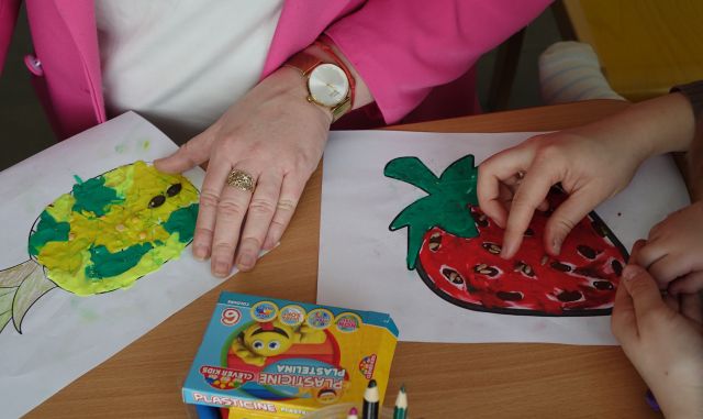 dorosłe dłonie wyklejają warzywa plasteliną