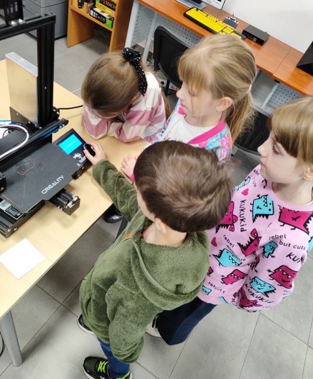 4 dzieci patrzy na drukarkę 3d