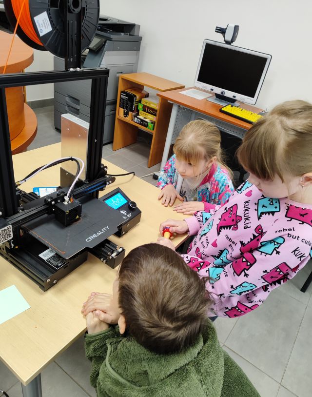 4 dzieci patrzy na drukarkę 3d