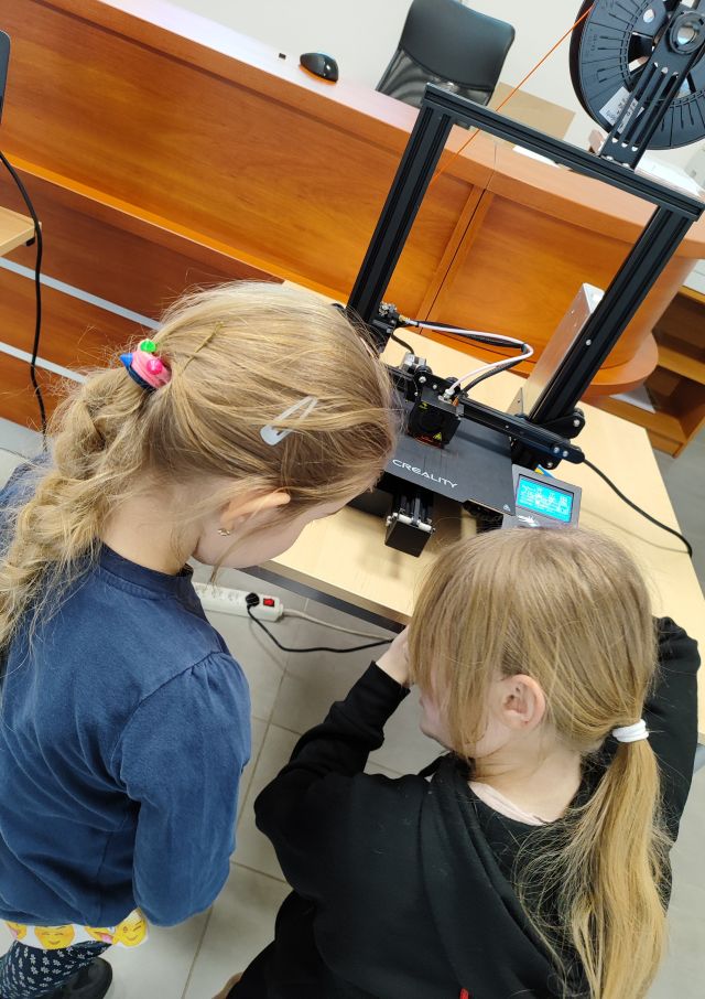 2 dziewczynki patrzą na drukarkę 3d