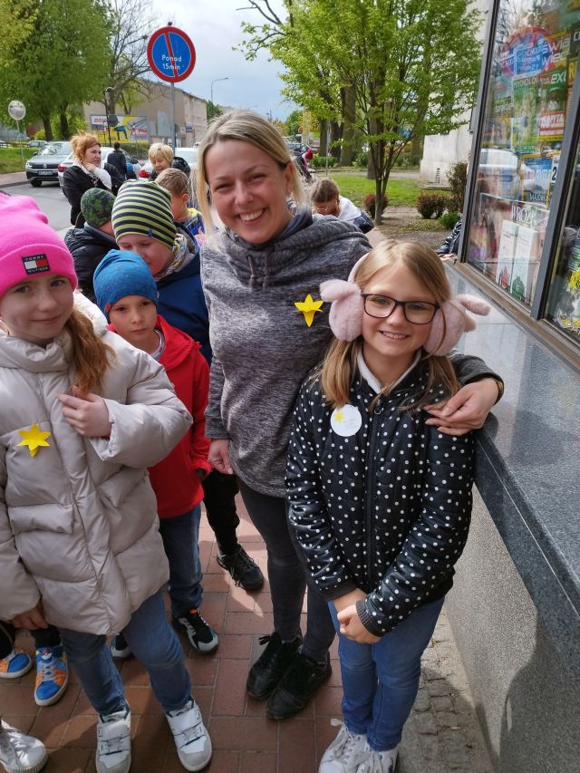 dzieci rozdają w miejście żółte papierowe żonkile