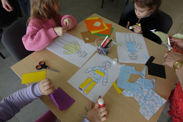 dzieci naklejają kolorowe materiały na naszkicowane na kartkach postacie cesarza