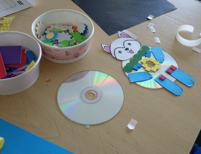 obok płyty CD leży wyklejony na płycie z różnych kolorowych kartek miś