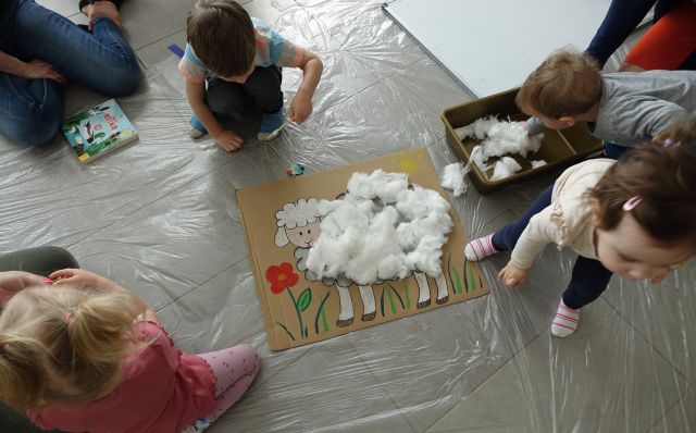 małe dzieci z pomocą rodziców wyklejają baranka z waty
